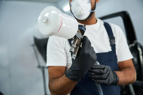 Skilled mechanic focuses intently while using a spray gun for auto body work in a garage. — Stock Photo