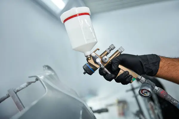 A skilled mechanic is applying paint to a car with precision in a well equipped garage. — Stock Photo