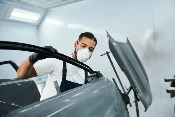 Un jeune mécanicien qualifié se concentre sur la réparation d'une voiture dans un atelier bien éclairé. — Photo de stock