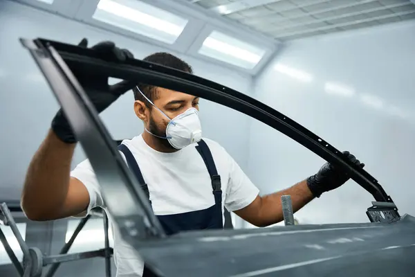 A young mechanic inspects and repairs a car part in a well lit workshop with precision. — Stock Photo