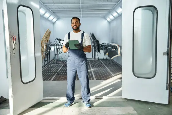 Young mechanic stands proudly in a bright workshop, ready to tackle his tasks for the day. — Stock Photo