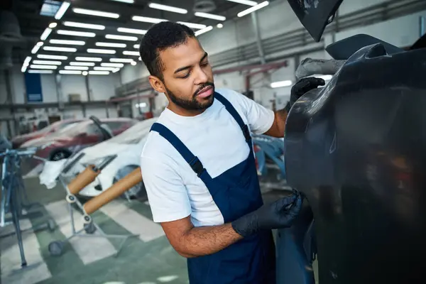 Skilled mechanic works diligently on a car in a well lit auto repair shop filled with vehicles. — Stock Photo