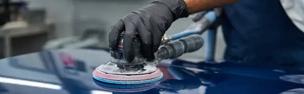 Skilled mechanic focuses intently on polishing a car surface with precision tools in a workshop. — Stock Photo