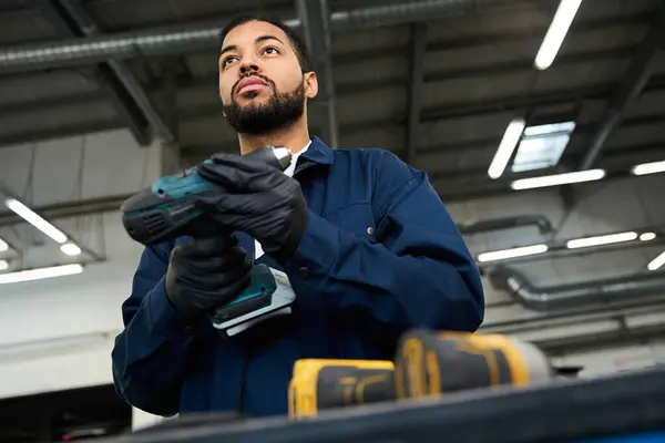 Mechanic demonstrates skills while holding tools in a well lit automotive workshop environment. — Stock Photo