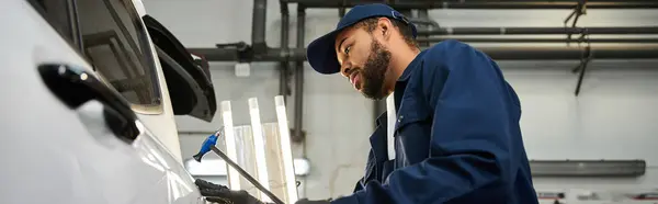 Mecânico dedicado com foco na precisão durante a realização de reparos em uma loja de automóveis movimentada. — Fotografia de Stock