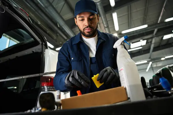 Focused mechanic organizes his tools and supplies while working in a bustling garage environment. — Stock Photo