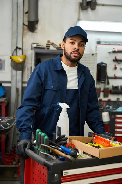 Handsome young mechanic focuses on his task in a busy garage, surrounded by tools and machinery. — Stock Photo
