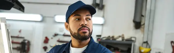 Handsome young mechanic focuses on tasks while surrounded by tools and equipment in workshop. — Stock Photo