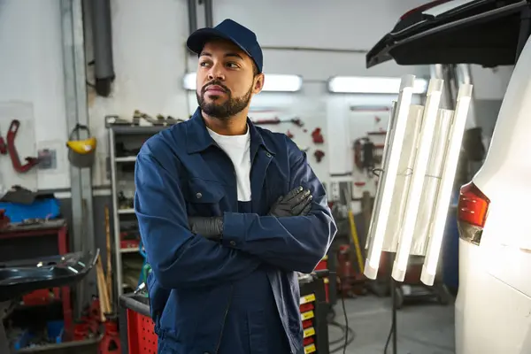 A skilled and attractive mechanic stands confidently while assessing a vehicle repair task — Stock Photo