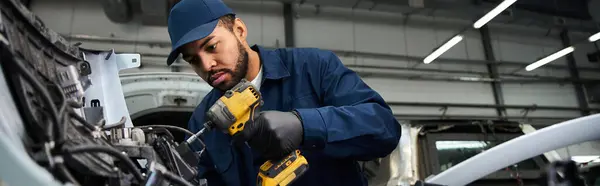 Handsome mechanic concentrates on repairing a vehicle with precision in an automotive shop. — Stock Photo