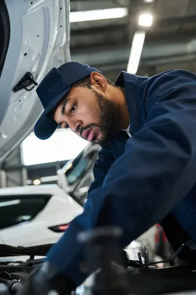 Handsome mechanic focuses on repairs in a well lit, modern garage during daylight hours. — Stock Photo