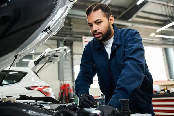 Handsome mechanic focused on repairing a car engine in a well equipped garage. — Stock Photo