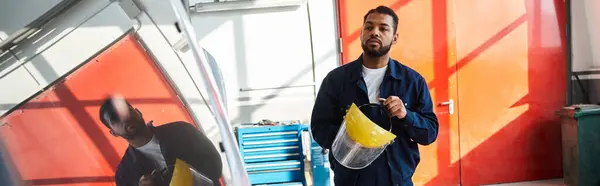 Jovem mecânico mostra suas habilidades enquanto trabalha com equipamentos em uma garagem brilhante. — Fotografia de Stock