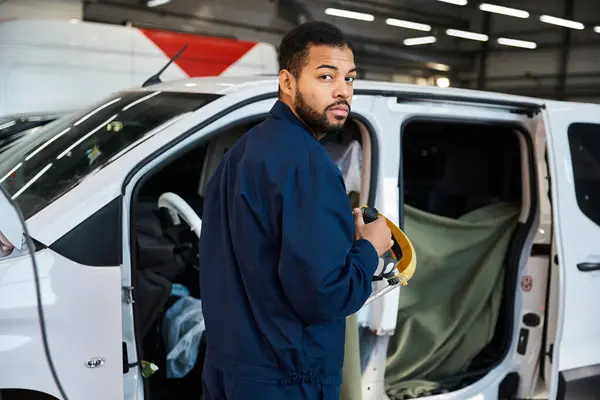 Young mechanic focuses on his task while surrounded by tools and vehicles in the garage — Stock Photo