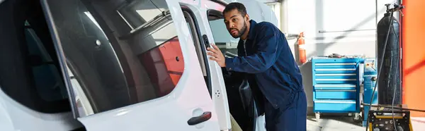A talented mechanic focuses intently while repairing a white vehicle in a spacious garage. — Stock Photo