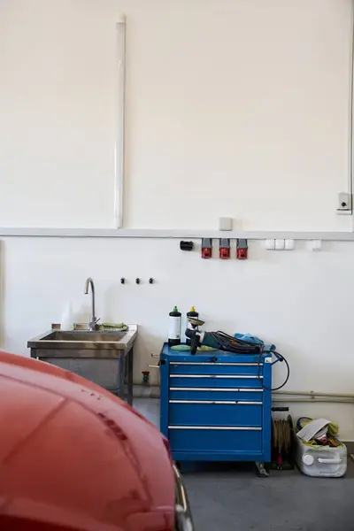 Red car in modern well lit garage next to sink and tools. — Stock Photo