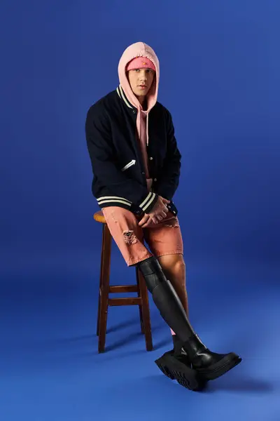 Joven con una pierna protésica posa en un taburete, mostrando un atuendo elegante en un entorno vívido. — Stock Photo