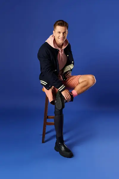 Joven orgulloso mostrando su pierna protésica mientras está sentado en un taburete con una sonrisa. — Stock Photo