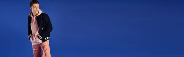 Stylish young man stands against a vivid blue backdrop, exuding confidence. — Stock Photo