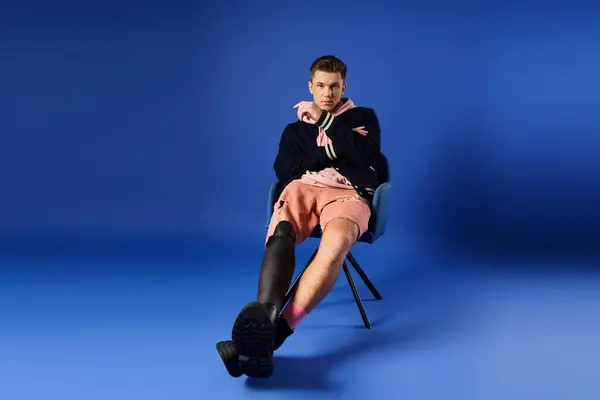 A young man in a prosthetic leg sits stylishly in a modern setting. — Stock Photo