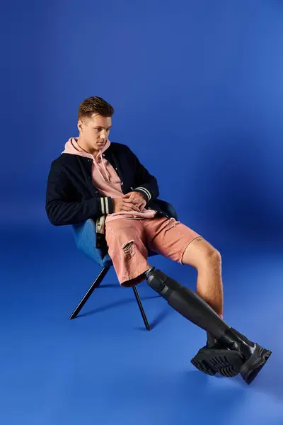 Young man in a chair with a prosthetic leg exudes style and confidence. — Stock Photo
