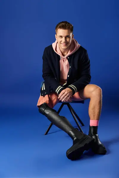 A confident young man in casual clothes smiles while seated with his prosthetic leg. — Stock Photo