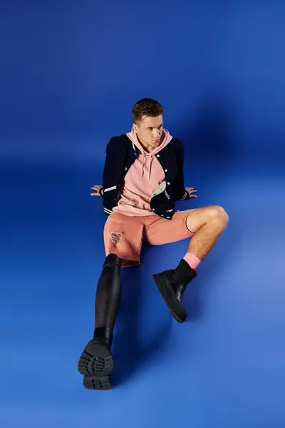 A young man with a prosthetic leg sits confidently on the ground dressed in casual attire. — Stock Photo