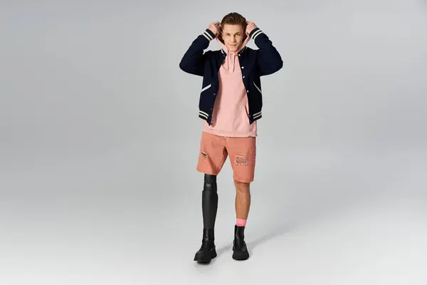 Young man confidently presents his fashionable attire and prosthetic leg in a contemporary space. — Stock Photo