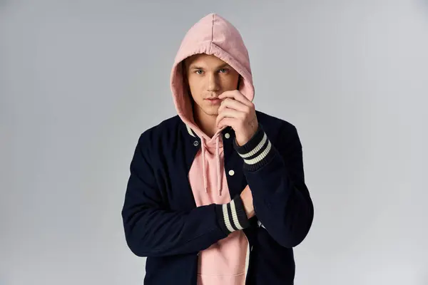 Joven confiado en sudadera con capucha y chaqueta, encarnando la fuerza. - foto de stock
