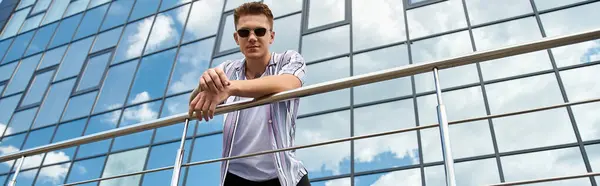 A confident young man stands in an urban setting and smiling at camera. — Stock Photo