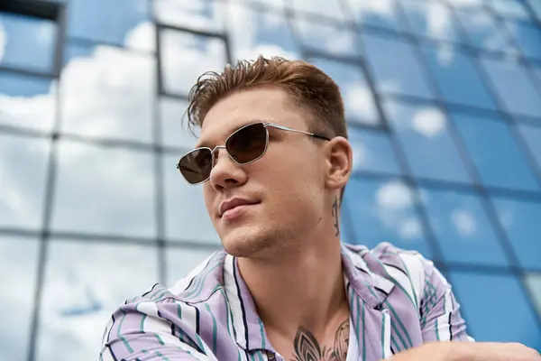 Молодий чоловік посміхається, насолоджуючись міською атмосферою в сонячний день. — стокове фото