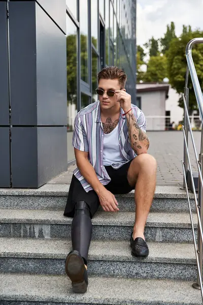 Handsome man with a prosthetic leg relaxes on steps in a busy city, enjoying the day. — Stock Photo