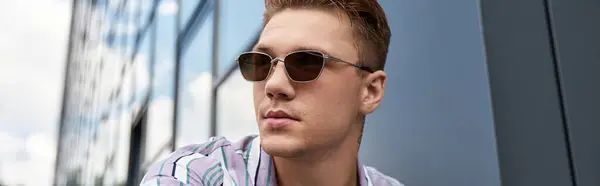 Handsome young man is relaxing in a modern urban setting, showcasing style. — Stock Photo