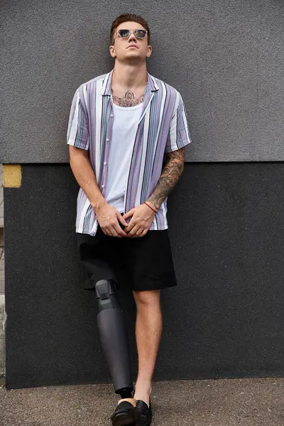 Young man with a prosthetic leg stands against a wall, showcasing his style and confidence. — Stock Photo