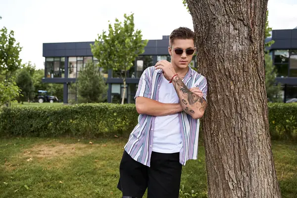 Handsome man with tattoos relaxes outdoors in a modern urban setting. — Stock Photo
