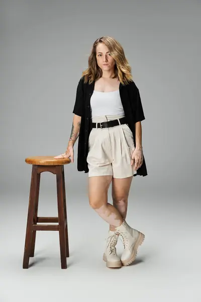 A woman with vitiligo stands by a stool, showcasing her unique beauty in a studio environment. — Stock Photo