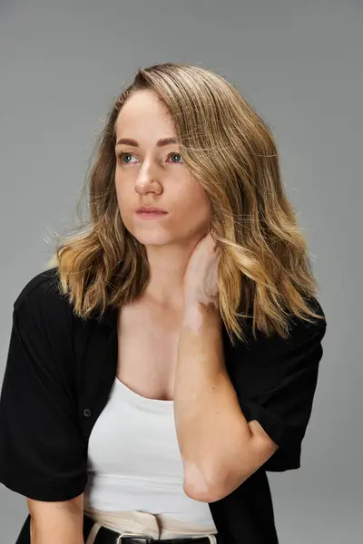 Mujer joven con vitiligo muestra su belleza y confianza en un fondo sencillo. - foto de stock