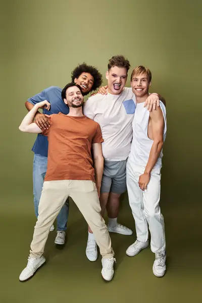 Four friends express joy and pride with vibrant poses and laughter in a studio setting. — Stock Photo