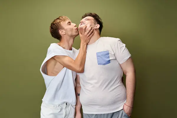 A queer couple joyfully kisses, celebrating love and connection in a cozy indoor setting. — Stock Photo