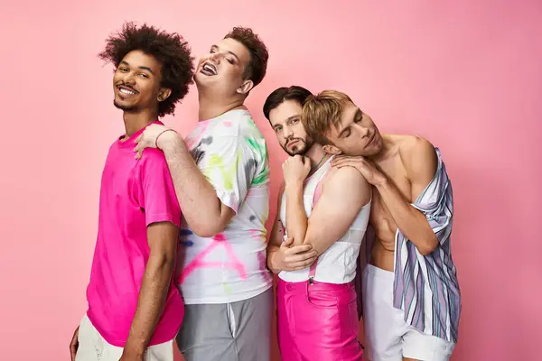 Four individuals express joy and pride in their vibrant outfits against a bright pink background. — Stock Photo