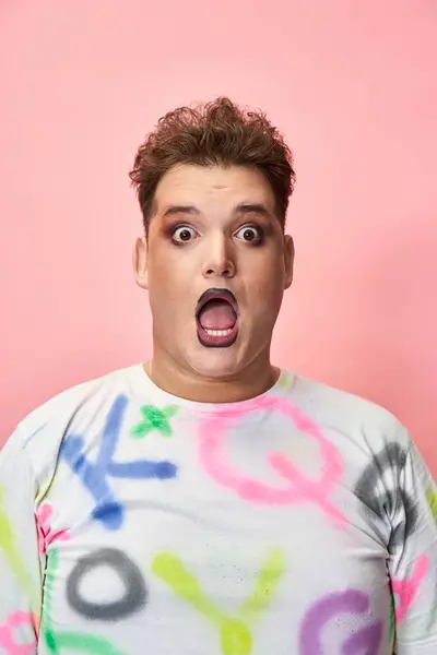 A person showcases a surprised expression while wearing a brightly decorated shirt. — Stock Photo