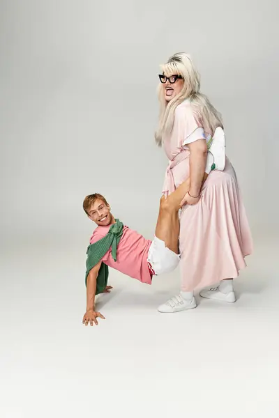 Two individuals showcase bold styles and playful energy in a colorful studio background. — Stock Photo