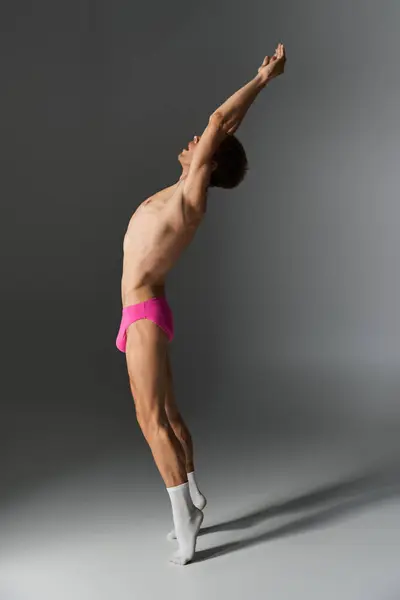 A dancer showcases grace and flexibility, arms raised, wearing pink shorts. — Stock Photo