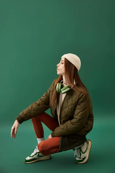 Young woman with anorexia sits thoughtfully against a green backdrop in casual attire. — Stock Photo