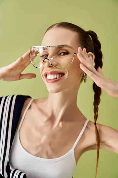 Jeune femme avec un sourire lumineux pose ludique devant une toile de fond verte. — Photo de stock