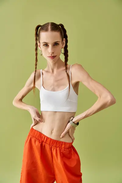 Une jeune femme montre sa bataille contre l'anorexie, debout avec confiance sur un fond vert. — Photo de stock