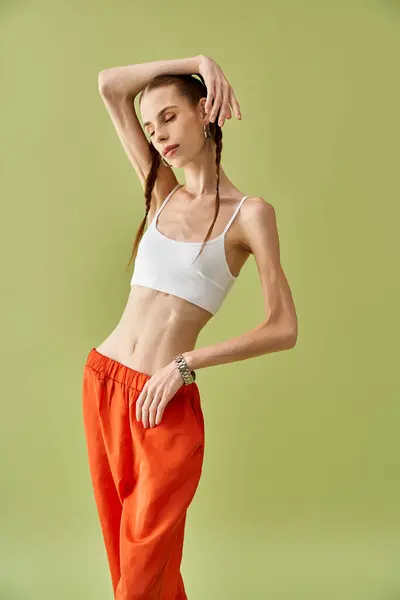 Une jeune femme pose gracieusement, révélant les effets physiques de l'anorexie sur fond vert. — Photo de stock