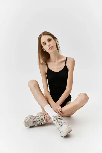 A young woman sits on the floor, expressing her struggle with anorexia through her pose. — Stock Photo