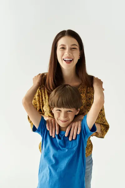 A cheerful young mother shares a playful moment with her son, both dressed casually and smiling. — Stock Photo