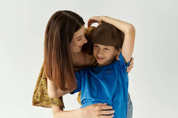 A young mother enjoys a playful moment with her son in casual attire, radiating love and warmth. — Stock Photo